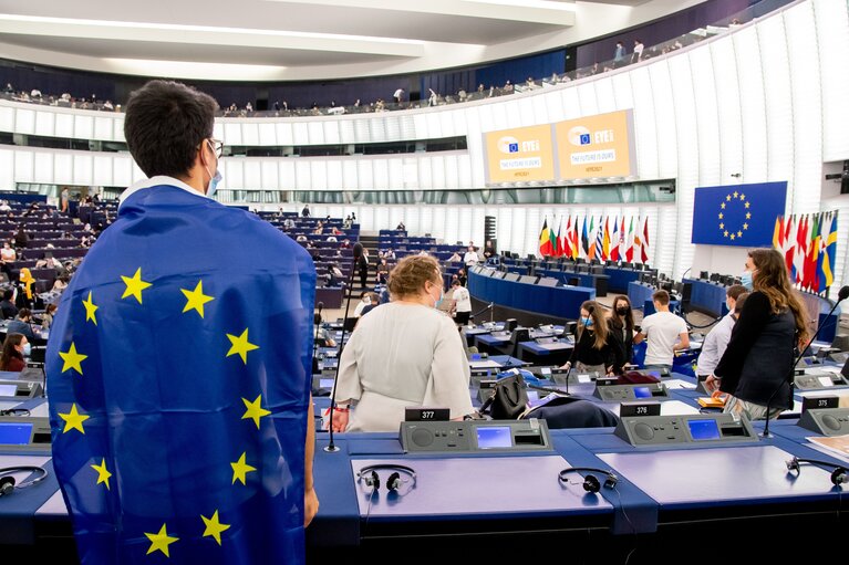Fotografía de un joven de espaldas con bandera europea sobre los hombros dentro del hemiciclo del Parlamento Europeo en Estrasburgo